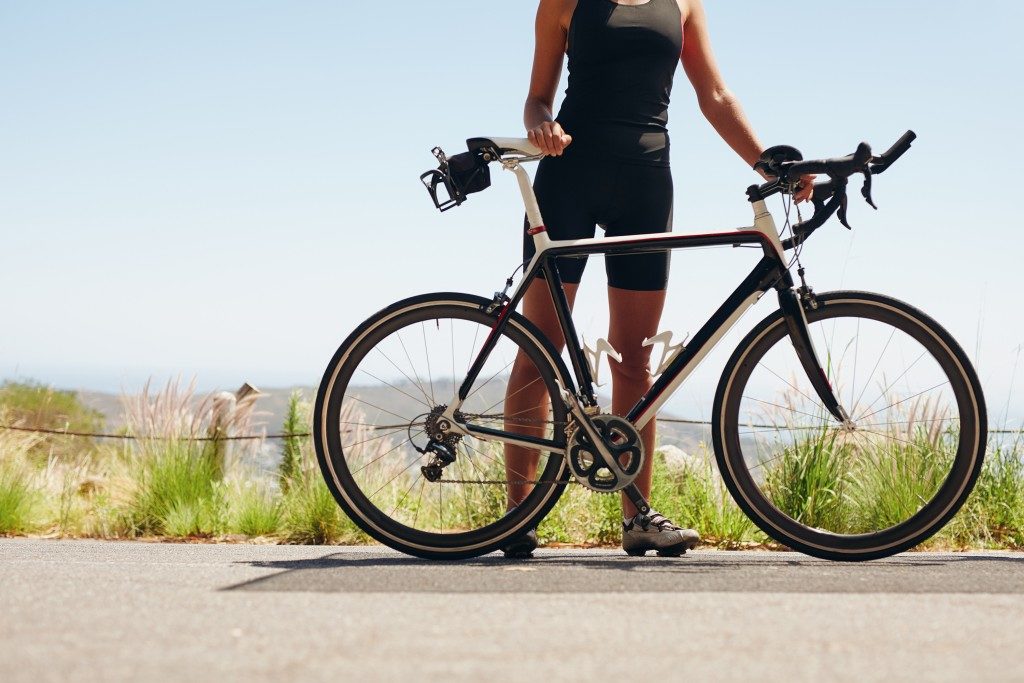 Woman cyclist with her bike on country road